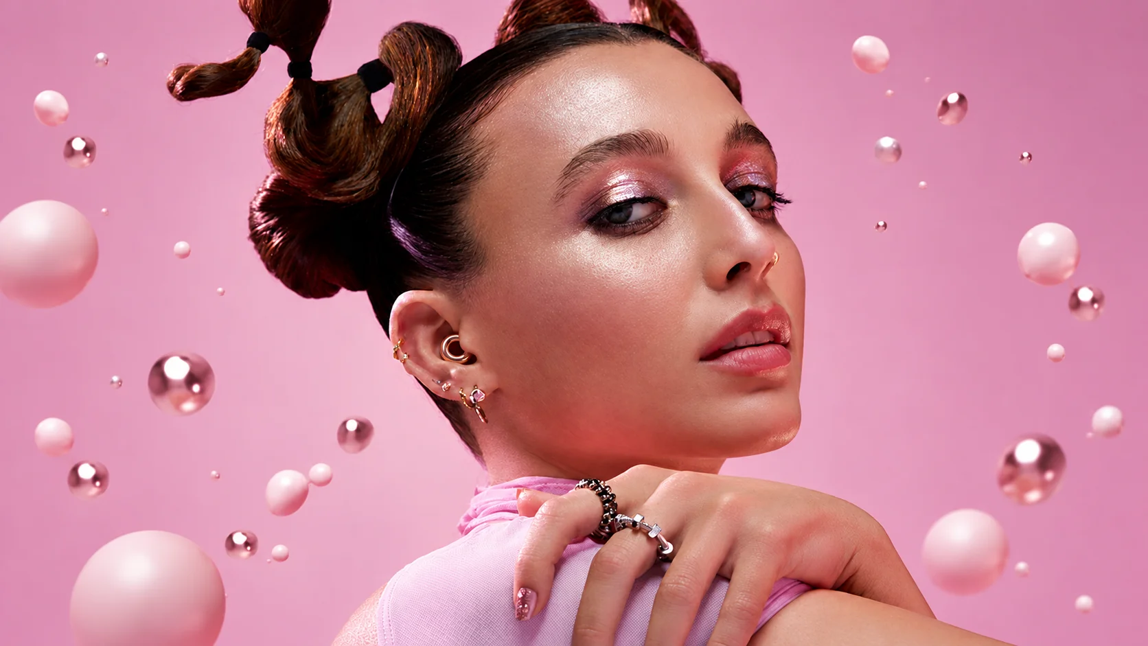Woman wearing a rose-gold Loop ring in her ear against a pink background