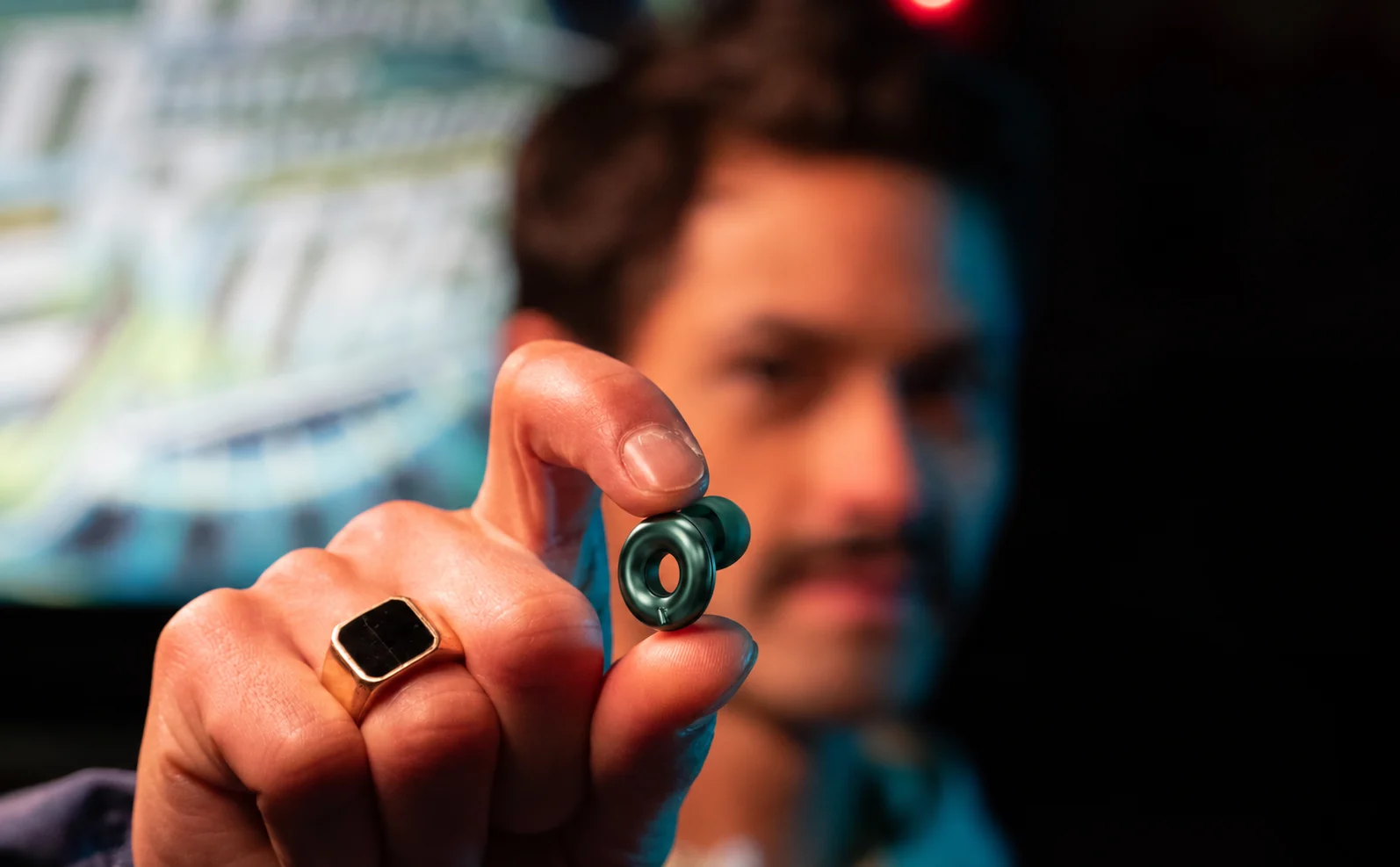 Person holding an emerald Loop earplug