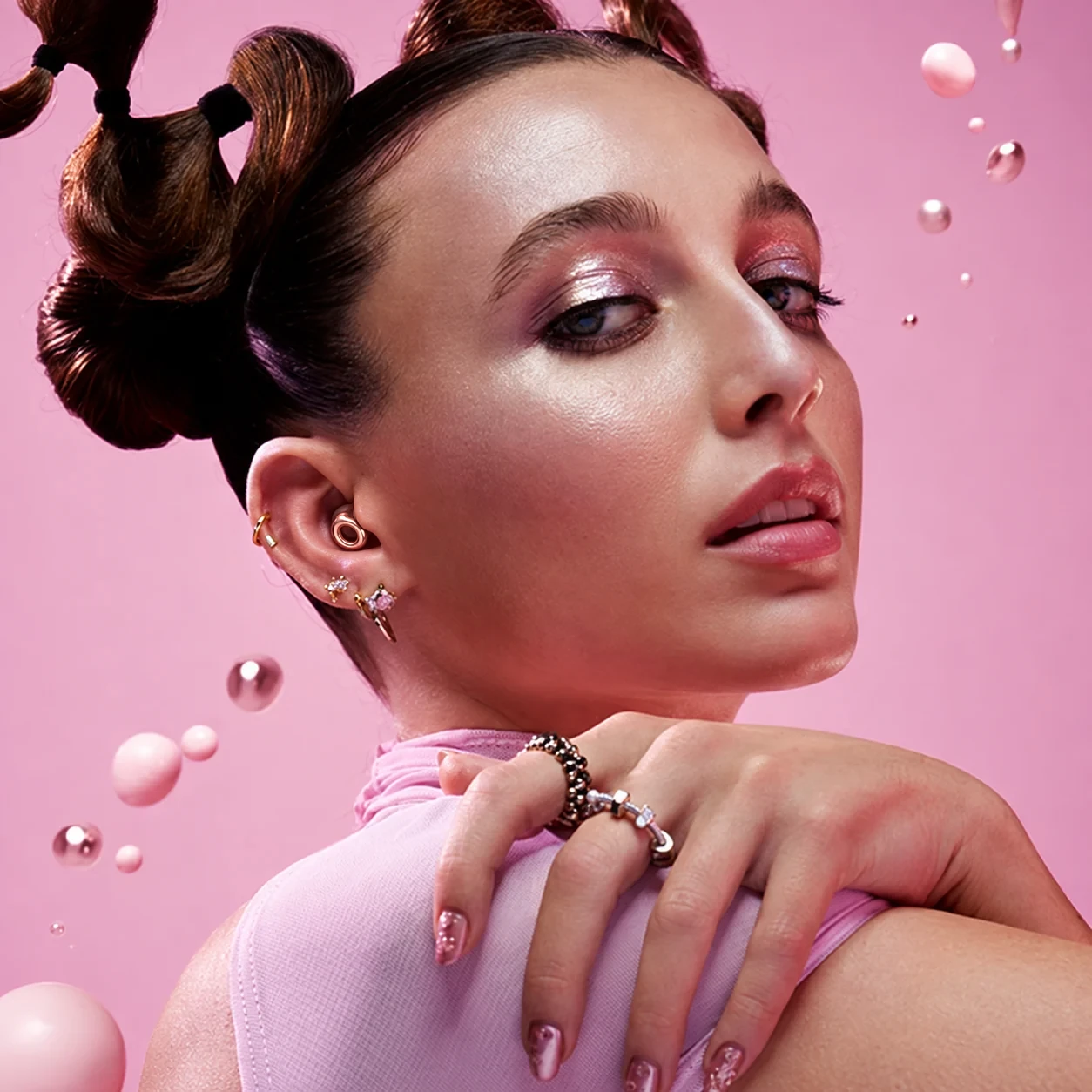 Woman wearing rose-gold Loop earplugs against a pink backdrop