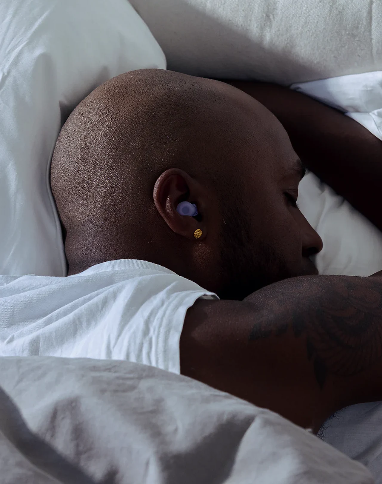 Side sleeper wearing lilac Loop Dream earplugs